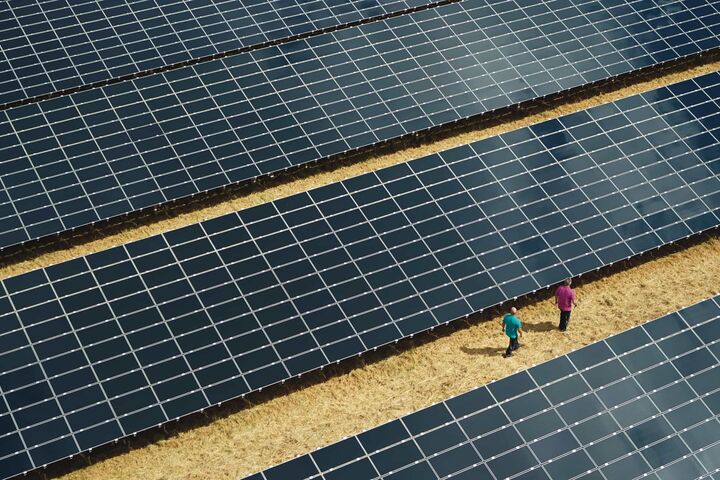 Luftansicht auf riesige Photovoltaikanlage mit zwei Menschen daneben