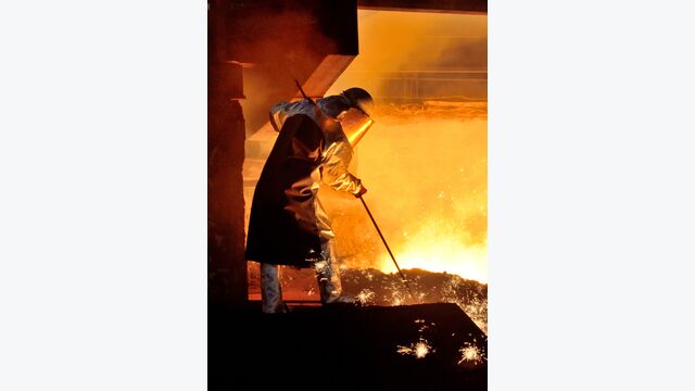 Ein Stahlarbeiter bearbeitet in Schutzkleidung heißen Stahl.